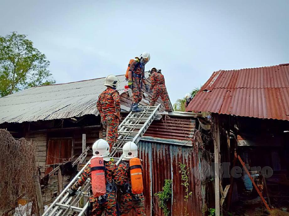 BOMBA berusaha membawa turun mayat yang sudah membusuk di atas bumbung rumah. FOTO Ihsan PDRM