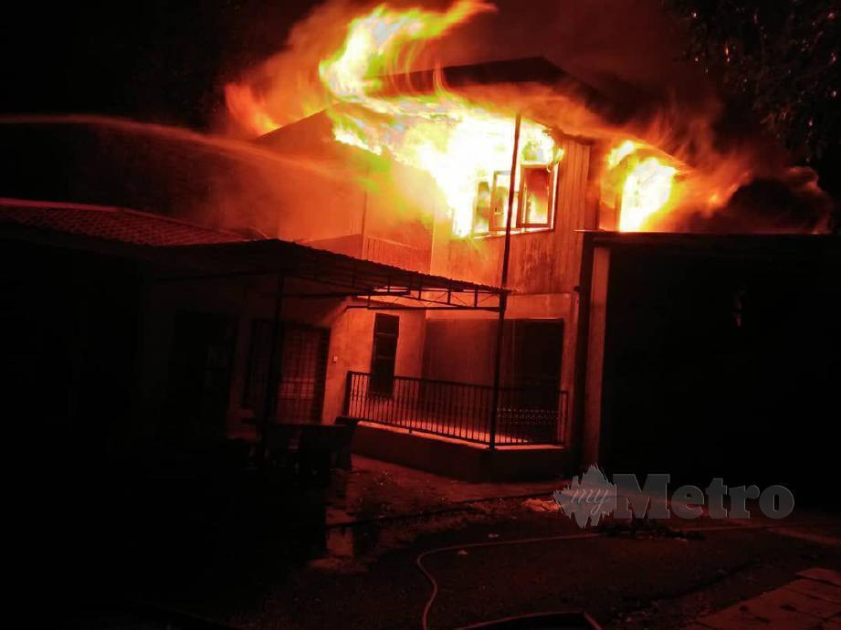 ANGGOTA bomba berusaha memadam kebakaran membabitkan sebuah rumah dua tingkat di Kampung Teluk Malek yang musnah 80 peratus. FOTO Ihsan Bomba