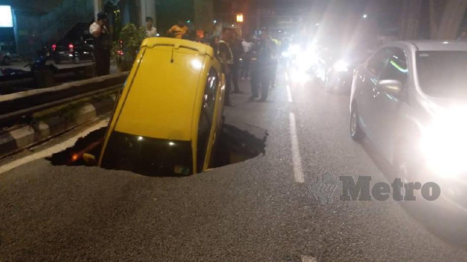 KERETA Perodua Myvi dipandu seorang wanita yang terjatuh ke dalam lubang akibat tanah mendap di Jalan Maharajalela menghala ke Jalan Loke Yew, Kuala Lumpur, semalam.  FOTO Ihsan PDRM