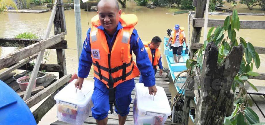 ANGGOTA APM membantu penduduk yang terjejas akibat banjir di Bintulu. FOTO ERIKA GEORGE
