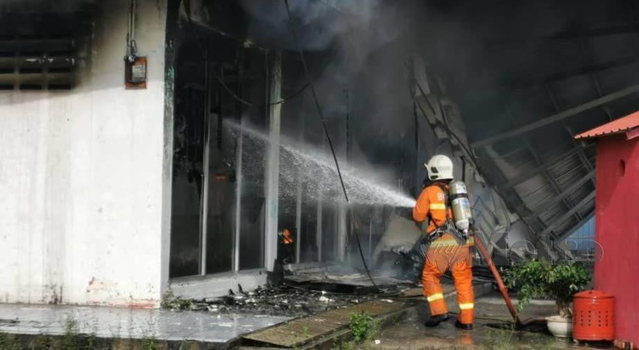 ANGGOTA bomba memadam api daripada merebak ke bangunan berhampiran. FOTO JUWAN RIDUAN