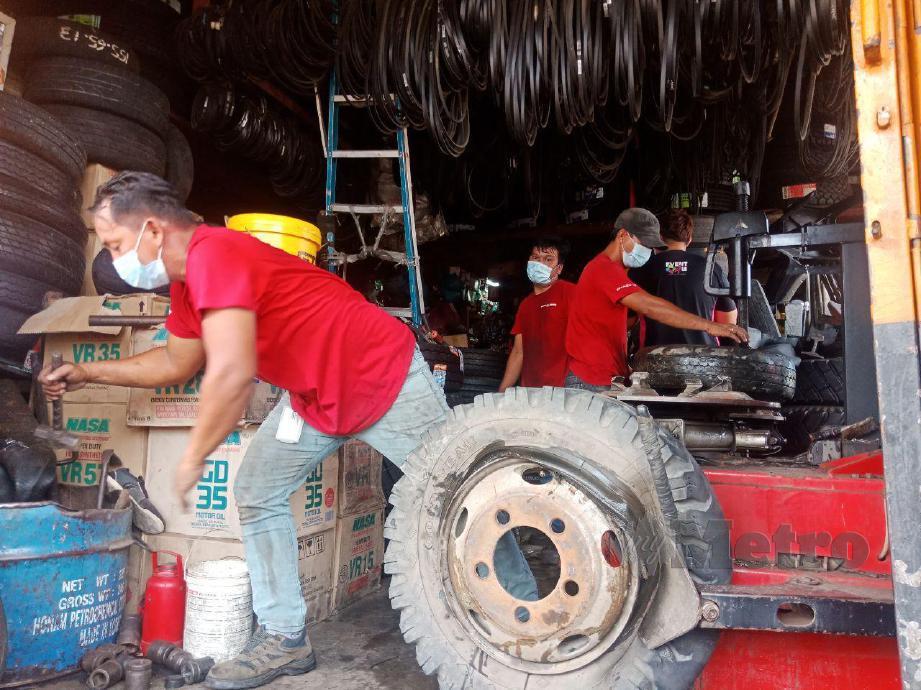 SEORANG pekerja kedai tayar sedang memperbaiki tayar kereta kepunyaan pelanggan. FOTO Rafiqah Dahali