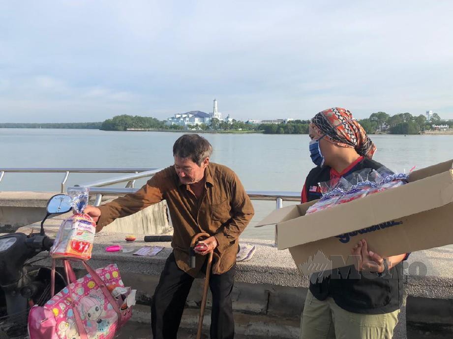 Zubaidah (kanan) menyerahkan sumbangan sebungkus roti Gardenia kepada golongan asnaf yang terpilih di Bandar Muar dan Kluang. FOTO IHSAN PEMBACA