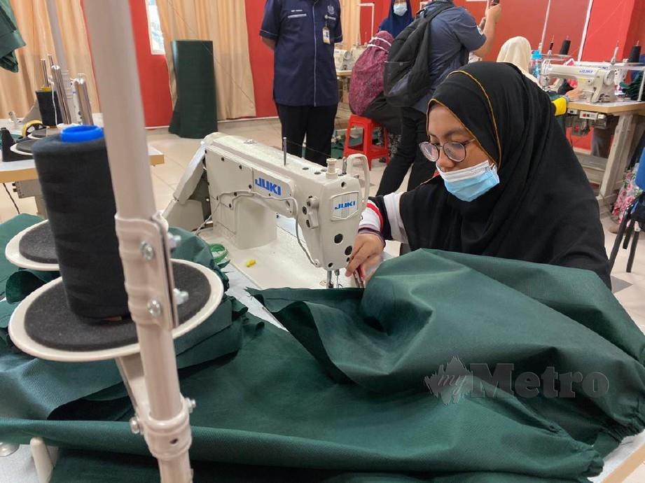 SITI tekun membantu menyiapkan projek jahitan pakaian perlindungan diri di Pusat Inkubator Jahitan USIM Nilai.
