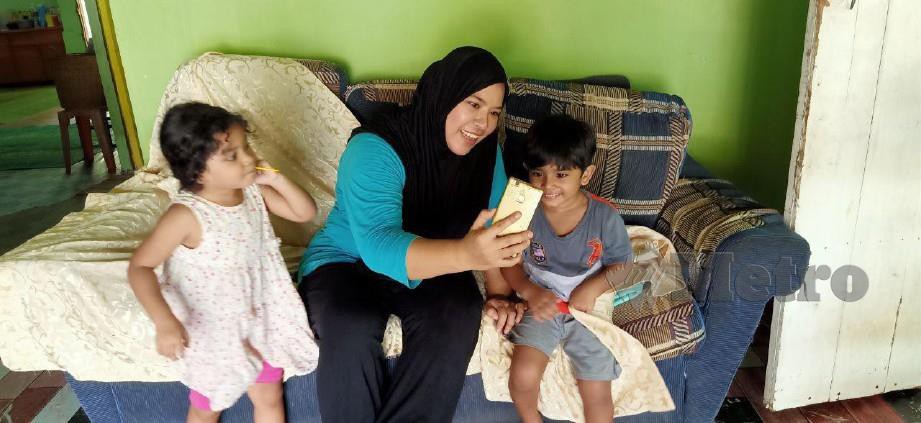 Nurul Husna Mohd Sharif bersama anak-anaknya sedang berbual dengan suami melalui panggilan video di Kampung Charok Semeliang, Siong. FOTO SAFURI KAMARUDIN.
