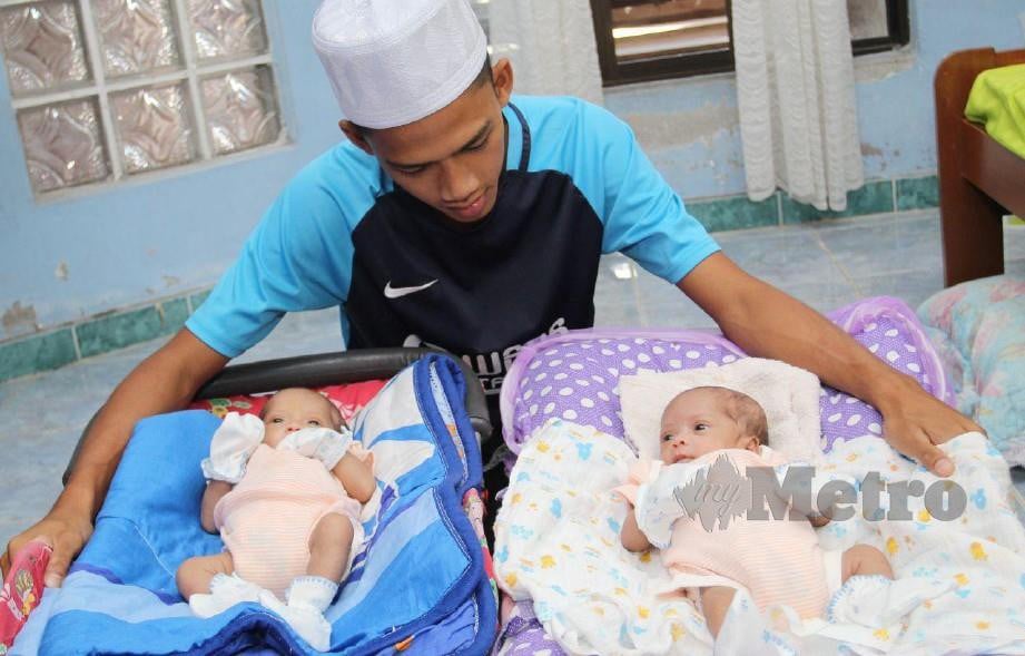 Syazwan memandang wajah bayi kembar yang dilahirkan isterinya, Siti Nur Nasuha yang telah meninggal dunia selepas dua minggu melahirkan bayi kembar tersebut. FOTO NIK ABDULLAH NIK OMAR.