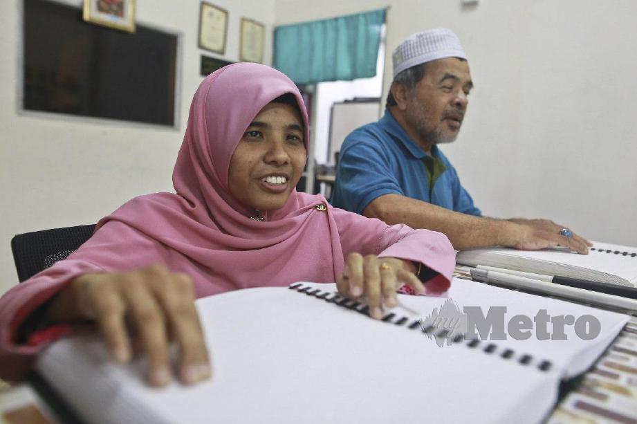 NOR Yusnita, 30 (kiri)  meluangkan masa mengajar ayahnya, Mohamad Awang, 68 membaca Al Quran menggunakan mushaf al- Quran dalam bentuk braille di Pejabat Persatuan Orang-orang Cacat Penglihatan Islam Malaysia (PERTIS) Seberang Takir. FOTO Ghazali Kori