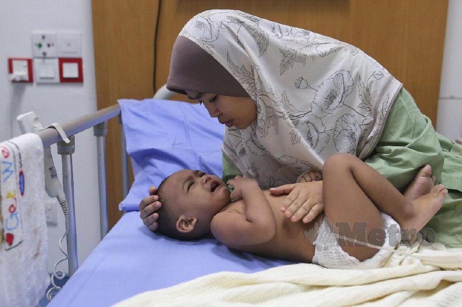 HASLINDA menemani anaknya, Wan Mohamad Hazim berusia setahun selepas mengalami keracunan makanan. FOTO Ghazali Kori