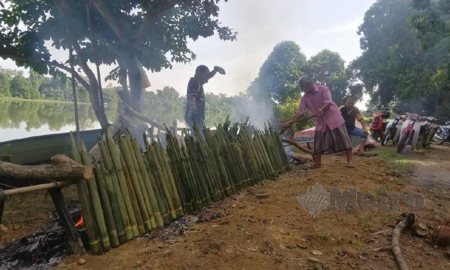 Jawatankuasa Dapur Kampung Prihatin sibuk membakar 400 batang lemang di kawasan sungai Kampung Pulau Manis, Serada. FOTO ZAID SALIM