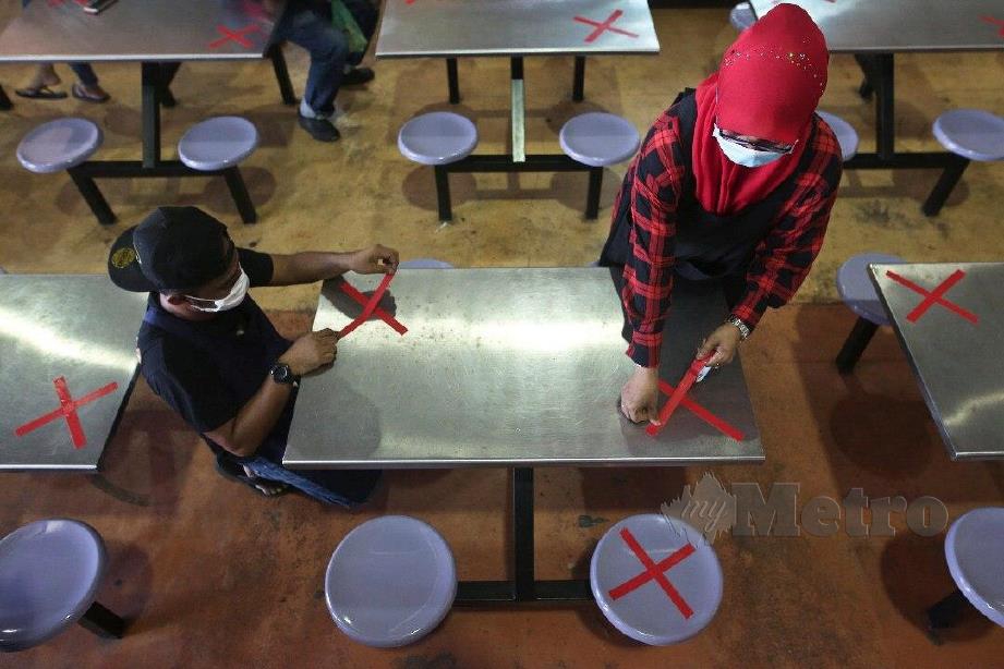 Wan Dalilah Wan Jaafar, 51 (tengah) meletakkan pita pelakat berbentuk 'X' menanda meja. FOTO GHAZALI KORI