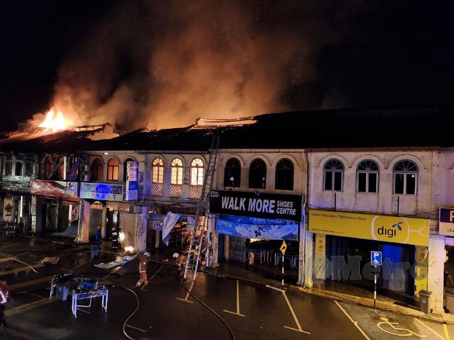 Anggota bomba bertungkus lumus memadam kebakaran membabitkan lima rumah kedai di Pekan Kuala Pilah, semalam, Foto Amran Yahya