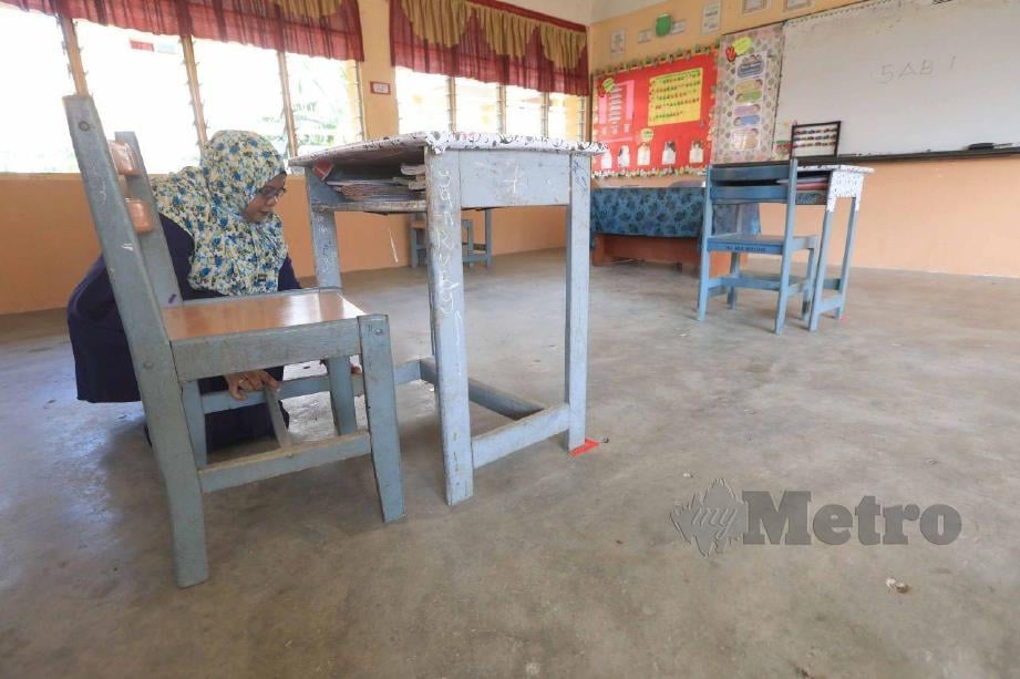 Kakitangan Sekolah Menengah Kebangsaan (SMK) Seri Pekan, Wan Nor Azirawati Ismail menyusun meja sebagai persiapan sesi persekolahan esok. Seramai sembilan pelajar dalam setiap kelas. FOTO MOHD RAFI MAMAT