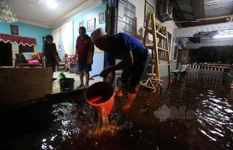 Penduduk Kampung Parit Rambai, Syazwani Azwin Mohd Kushari bersama ahli keluarga menyelamatkan barang keperluan asas dan dokumen penting selepas kediaman mereka dimasuki air banjir berikutan hujan sejak awal pagi tadi. FOTO MOHD AZREN JAMALUDIN