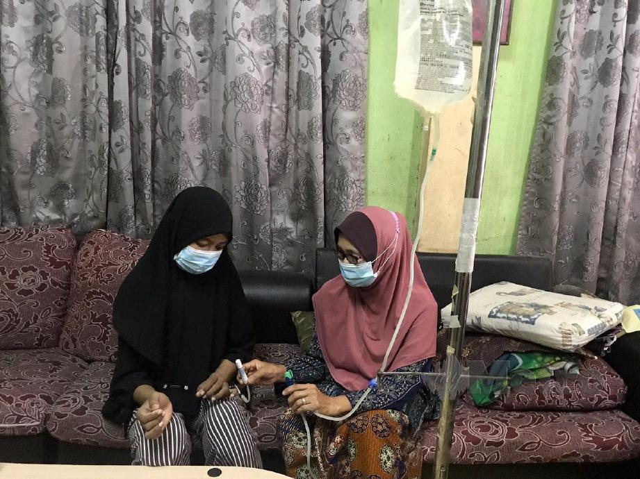 Rozainita Rahim (kiri) dibantu ibunya, Hawiah Mohamed menjalani Continuous Ambulatory Peritoneal Dialysis (CAPD) ketika ditemui di rumahnya di Kampung Kedai Buloh. FOTO HAZIRA AHMAD ZAIDI