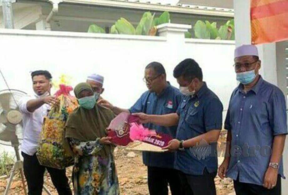 Mohd Azwan (kanan) menyerahka replika kunci rumah zakat MAIK kepada seorang dari keluarga miskin di Chiku 3, hari ini. FOTO RAMLI IBRAHIM