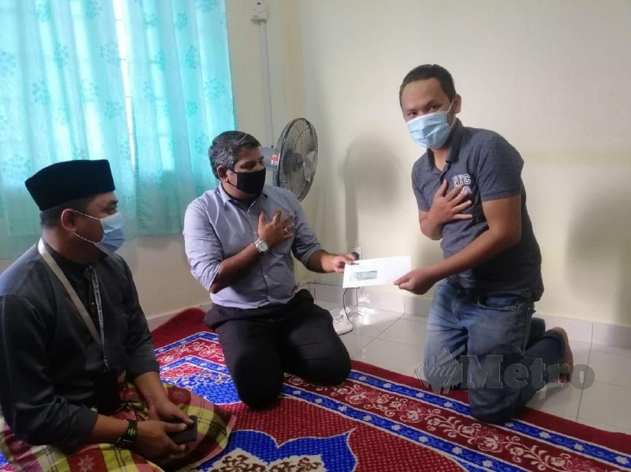 Abdul Basith Hamid menyerahkan sumbangan kepada Mohd Iddham mewakili keluarganya. FOTO RUWAIDA MD ZAIN