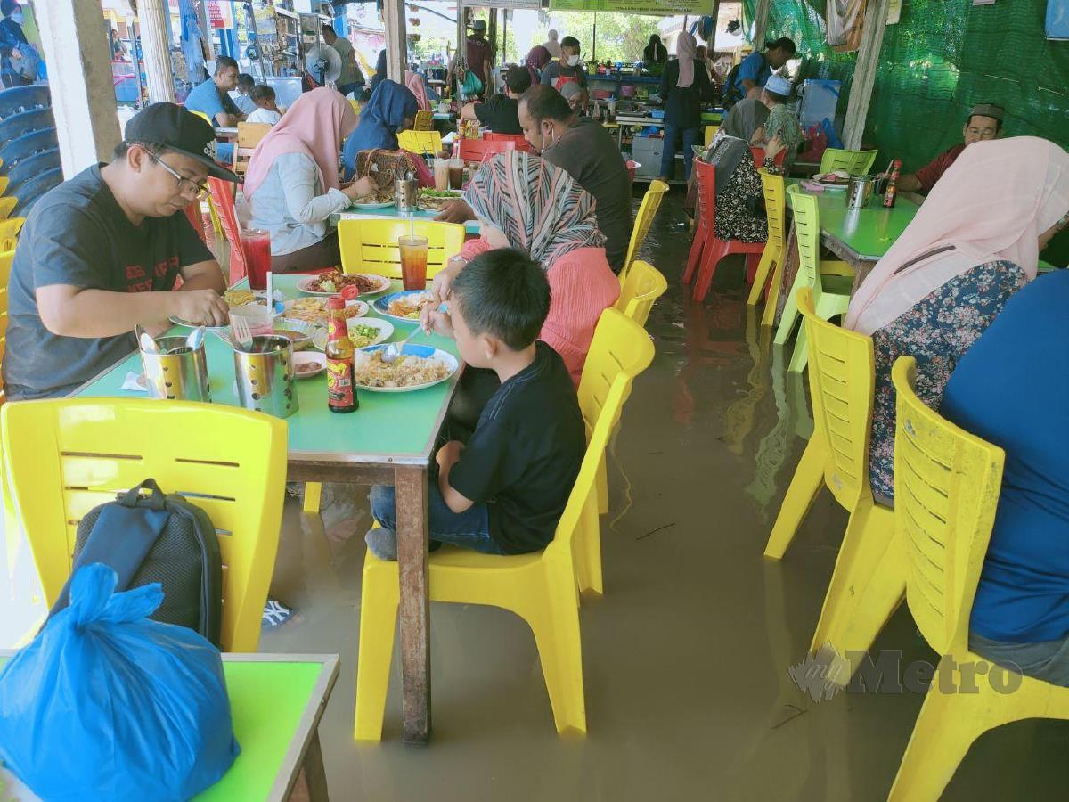 Pengunjung yang datang ke kedai makan di pelantar ikan Kuala Kedah menikmati makanan berendam kaki dalam air berikutan air pasang besar yang berlaku di Kuala Kedah. FOTO ZULIATY ZULKIFFL