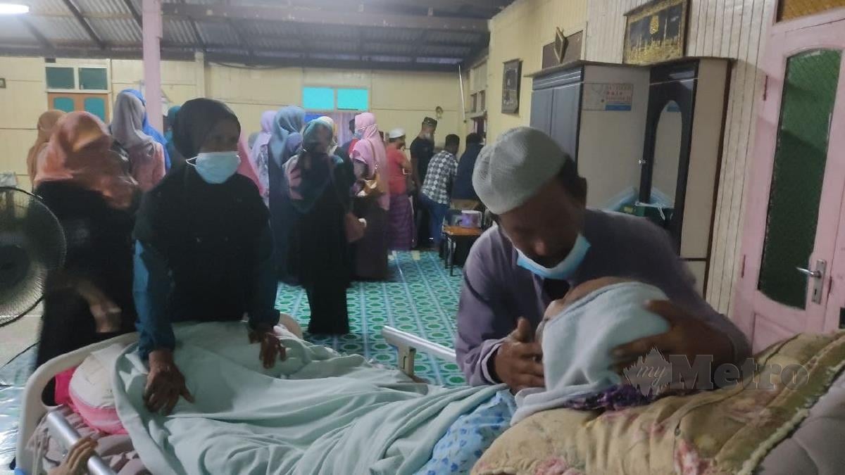 Ismail berkata sesuatu kepada isterinya, yang terlantar di katil kerana menghidap kanser otak tahap tiga sebaik jenazah diusung keluar dari rumah keluarganya di Kampung Beladau Kepong. FOTO ZAID SALIM