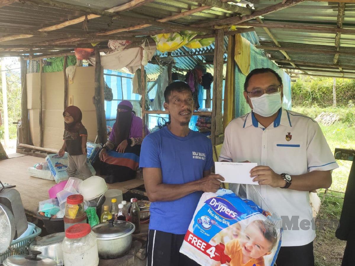 Pegawai Daerah Kuala Pilah, Mohd Faizal Abdul Manap (kanan) bertanya sesuatu kepada Zairiman Aziz ketika melawat keluarga terbabit di Kampung Guntur, Batu Kikir. FOTO Amran Yahya.