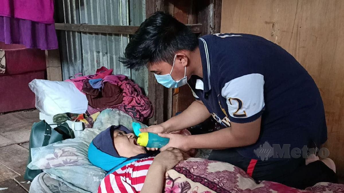 CHE Muhammad Arif menyuap air minuman kepada ibunya, Junaidah yang terlantar akibat serangan angin ahmar. FOTO Siti Rohana Idris