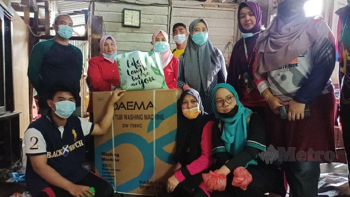 WAKIL POKB menyerahkan mesin basuh untuk kegunaan Junaidah sekeluarga. FOTO Siti Rohana Idris