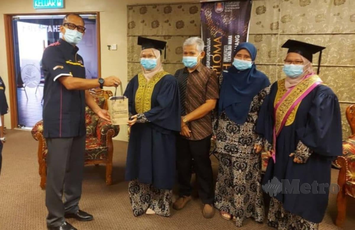Dr Mohd  Ilham Adenan (kiri) menyampaikan cenderamata kepada graduan UiTM, Norsyazwana Mohd. Ramly selepas majlis penganugerahan diploma dan ijazah secara janji temu di UiTM Pahang di Jengka, Maran hari ini. FOTO ROSELAN AB MALEK