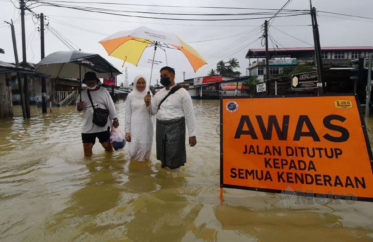 Wan Muhammad Ridhwan  dan Nor Aishah terpaksa meredah banjir selepas selesai majlis akad nikah di Masjid Jubli Perak Sultan Ismail Petra. FOTO NIK ABDULLAH NIK OMAR