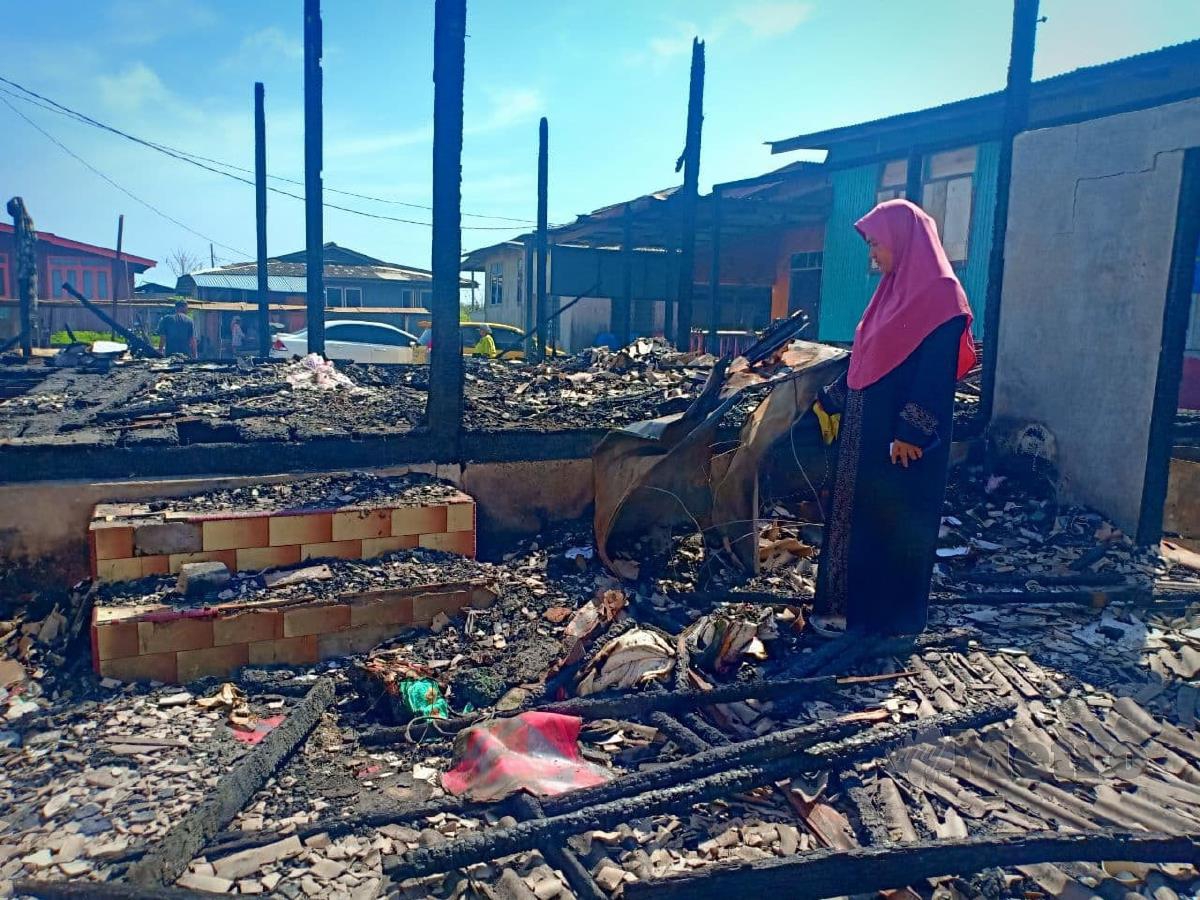 Asnah melihat peti sejuk beku miliknya yang hangus. FOTO AHMAD RABIUL ZULKIFLI