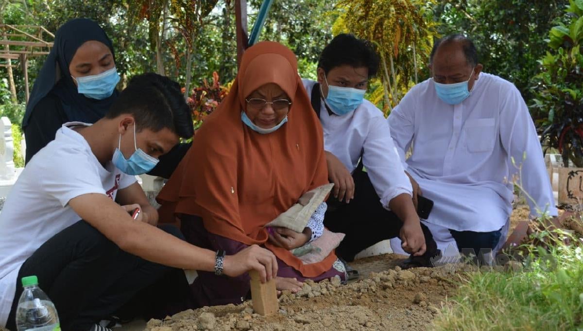 Norlida dan Md Tarmidi Yaaccob (kanan) bersama ahli keluarga di kubur Adik di Tanah Perkuburan Islam Padang Lebar, Simpang Bekoh, Jasin. FOTO AMIR MAMAT