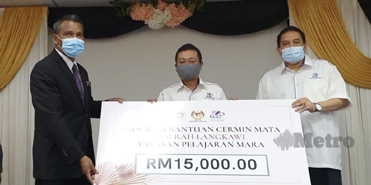 Mohd Nizar Sudin (tengah) menyerahkan replika cek bernilai RM15,000 kepada Timbalan Pegawai Pendidikan Daerah Langkawi (Pembangunan Murid) Ismail Man (kiri) di Pejabat Pendidikan Daerah Langkawi. FOTO HAMZAH OSMAN