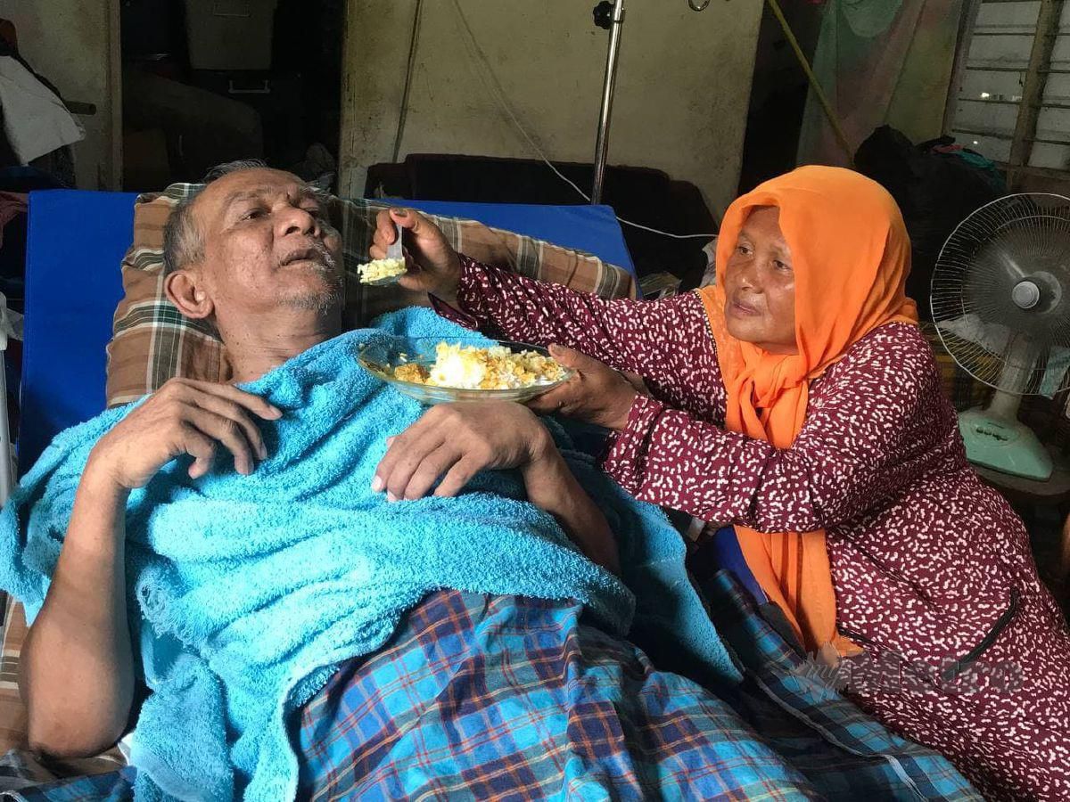 HAMINAH menyuapkan makanan kepada suaminya, Mamat Isa yang terlantar sejak lebih dua tahun lalu. FOTO Hazira Ahmad Zaidi