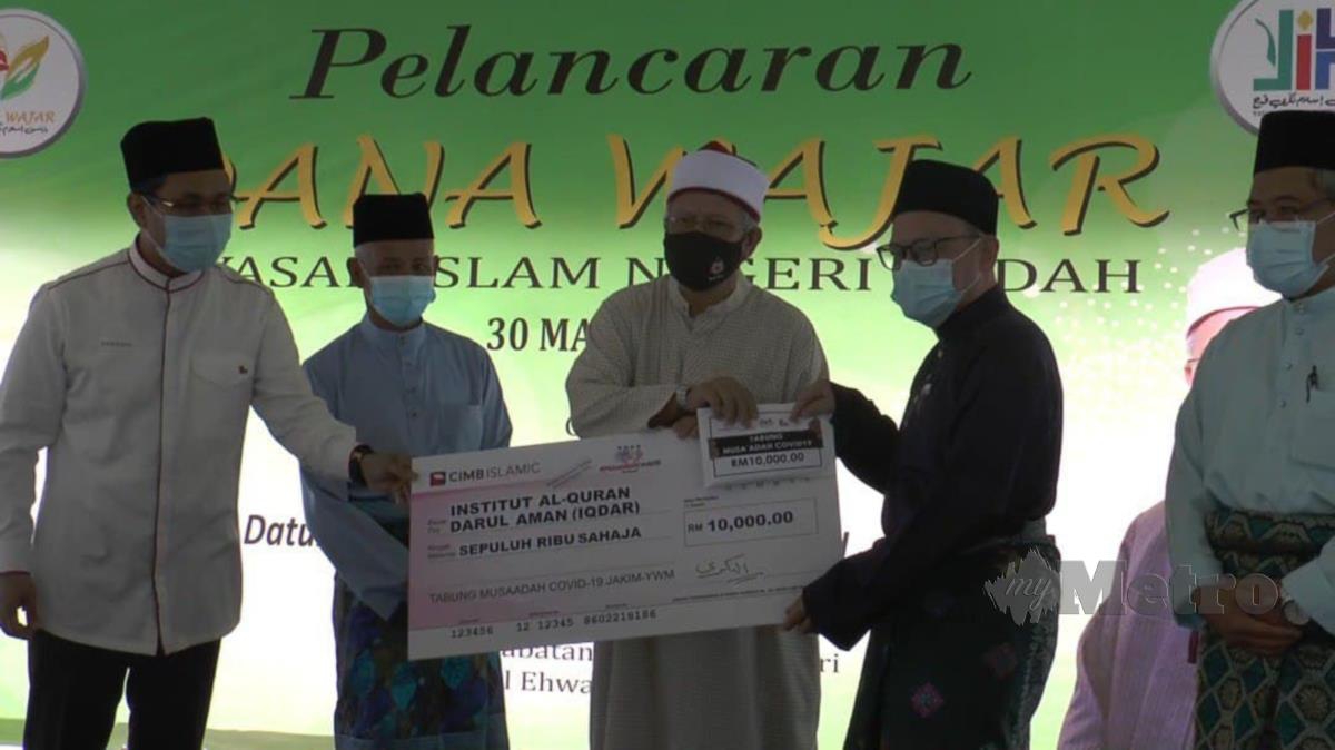 Dr Zulkifli Mohd Al Bakri menyerahkan mok cek Musaadah COVID 19 sebanyak RM10,000 kepada Pengarah IQDAR, Syeikh Kadri Abdul Hamid. Foto Noorazura Abdul Rahman