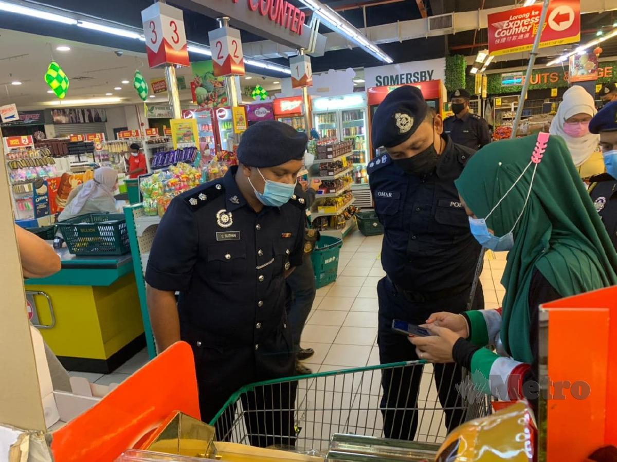 Omar Sappi (tengah) memeriksa pendaftran masuk di Mysejahtera pelanggan pada pemeriksaan SOP PKP 3.0 di pasar raya di Manjung. FOTO NOOR HIDAYAH TANZIZI