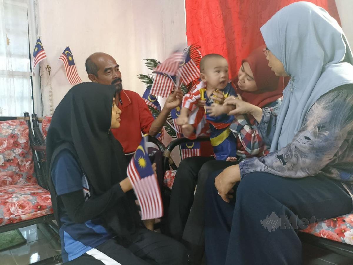 Wafi Rizqi Yang lengkap berpakaian Jalur Gemilang dikelilingi ibunya, Nur Zahidah (kanan), nenek dan datuknya, Norhayati dan Mohd Zauki serta, ibu saudaranya Nur Zulaikha (kiri) di rumah mereka di Kampung Bukit Agu, Batu Rakit. FOTO ZAID SALIM