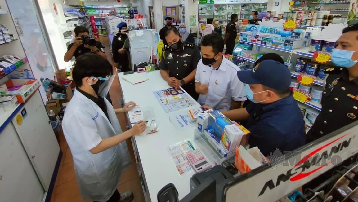 Zikril  (dua dari kanan) melihat kit ujian kendiri Covid-19 yang dijual di sebuah farmasi di Sekinchan. FOTO AMIRUL AIMAN HAMSUDDIN 