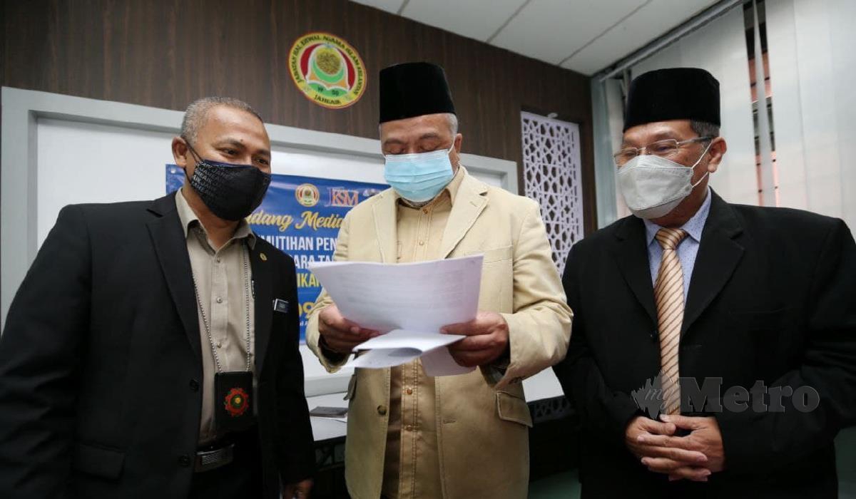 Che Mohd Rahim (tengah) bersama pegawainya memeriksa dokumen sindike. FOTO NIK ABDULLAH NIK OMAR