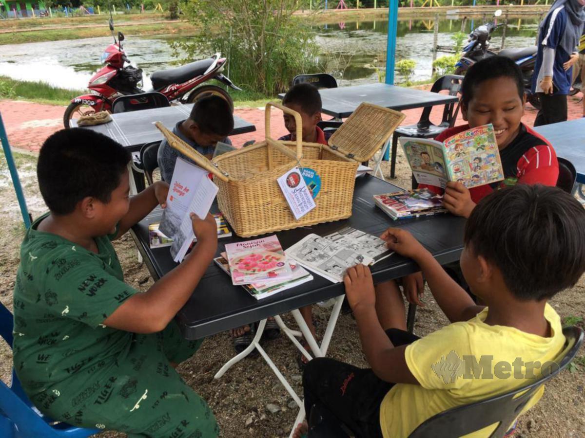 ANAK-anak penduduk kawasan perumahan KEDA, Teluk Berembang sedang asyik membaca komik dan buku yang berada dalam bakul.