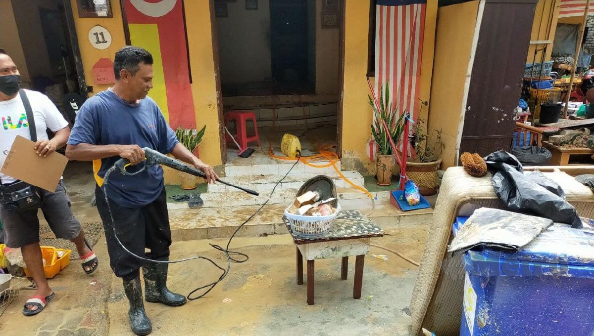 Penduduk Kampung Lembah Jaya Utara, Hassan Mohd Sharif, 56,  mencuci barangan rumahnya yang diselaputi lumpur selepas kediaman mereka dilanda banjir kilat. Foto Muhaamad Hafis Nawawi