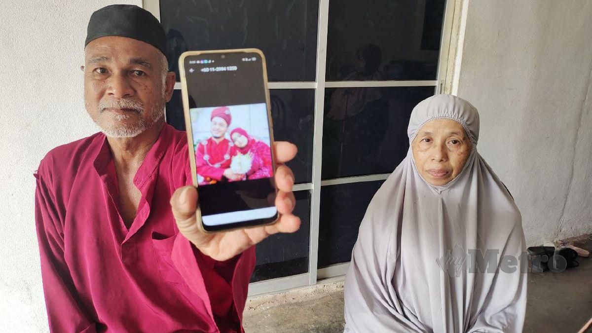 Siti Esah bersama suaminya Wan Abd Razak Wan Sulaiman, 59, yang menunjukkan gambar perkahwinan arwah anak mereka Jumaat lalu. FOTO Syaherah Mustafa