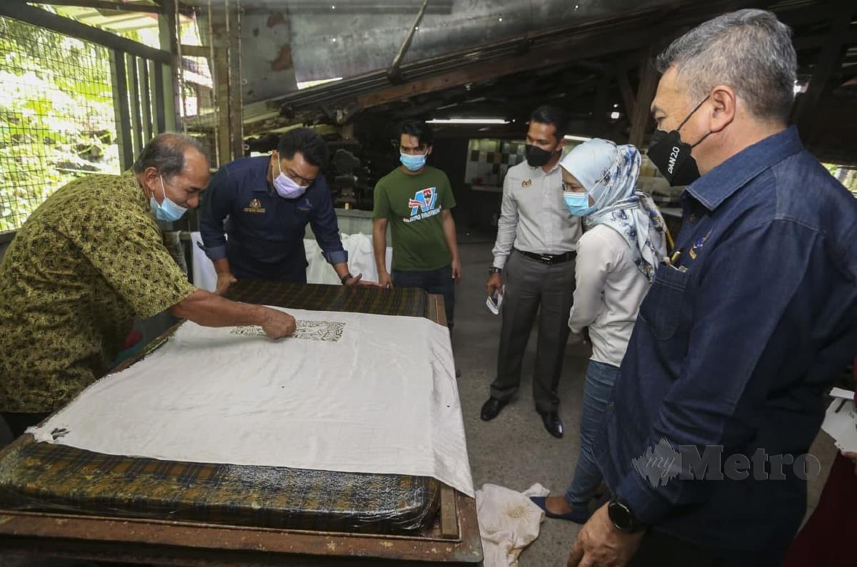 Badrul Hisham (dua kiri) melihat Pengurus Ayu Craft Kraftangan dan Hasil Rimba, Mahadi@Ibrahim Deraman (kiri) menunjukkan teknik menekap batik ketika melawat bengkel perusahaan Ayu Batik sempena rangka kerja lawatan di Kampung Talak. FOTO NIK ABDULLAH NIK OMAR