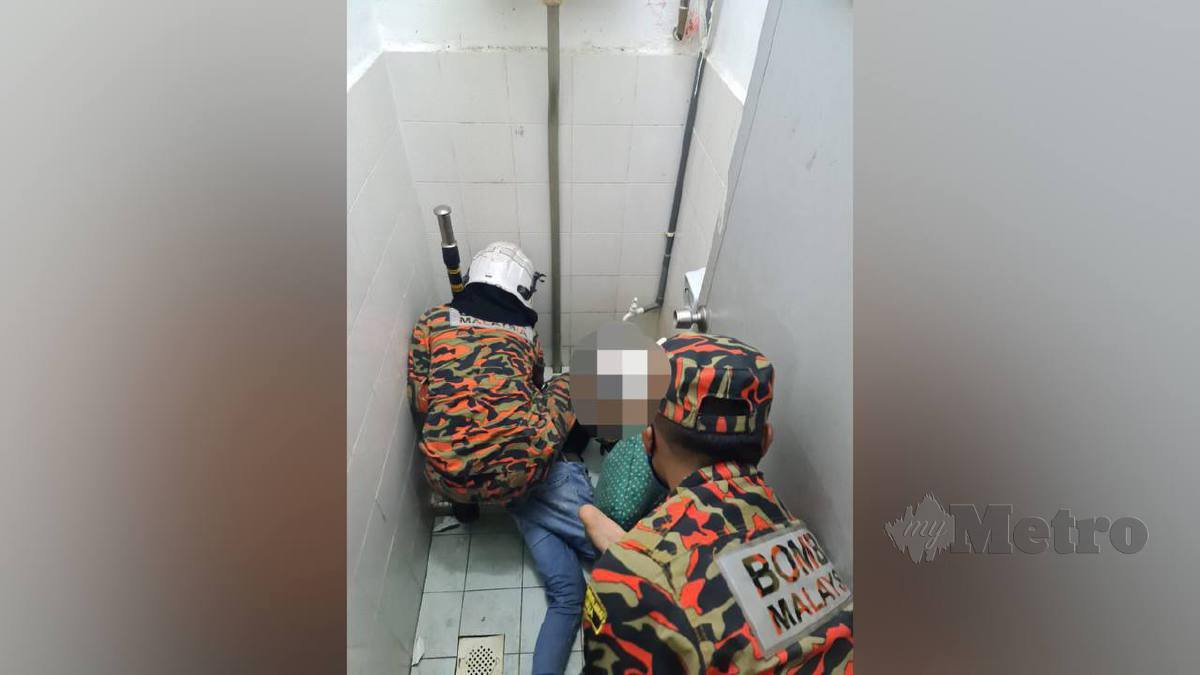 Anggota bomba membantu mengeluarkan tangan mangsa yang tersepit dalam lubang tandas. FOTO Ihsan Bomba