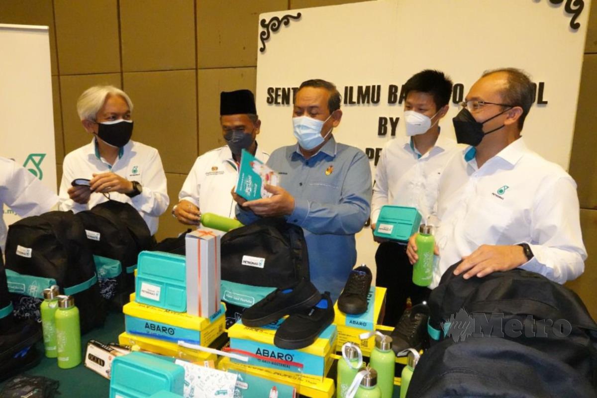 Aminuddin Harun (tengah) melihat barangan keperluan sekolah sumbangan PETRONAS  sewaktu sesi penyerahan Program 'Back to School' 2022 di Seremban. Ihsan Petronas