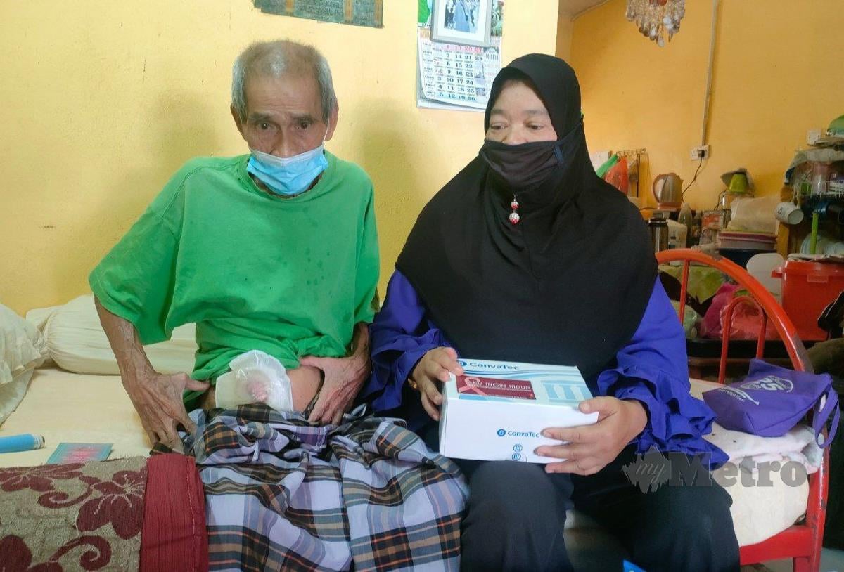 Mohamad Salim pesakit kanser usus menunjukkan beg stoma yang digunakannya di samping isterinya, Azizah Ismail, 57, di rumah mereka di Taman Mawar, Hutan Kampung. FOT ZULIATY ZULKIFFLI