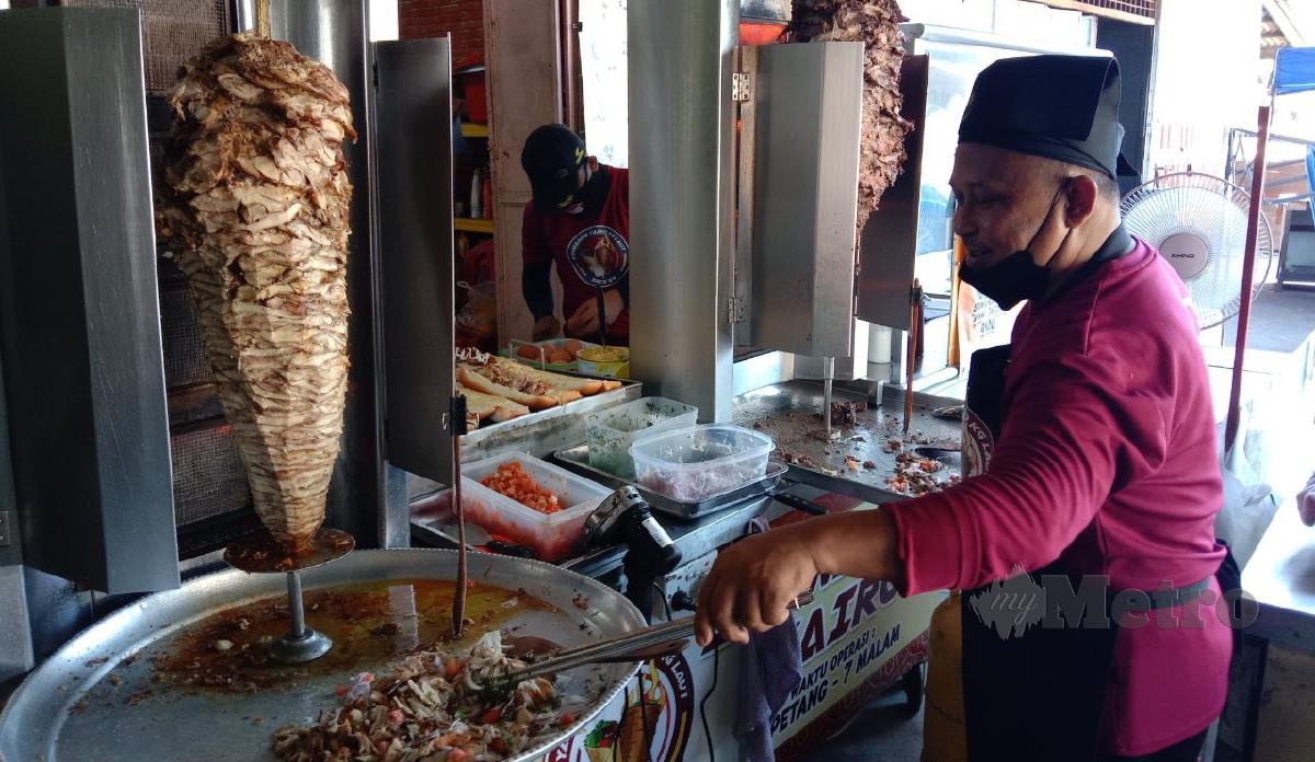 Che Rosdi sedang memotong daging untuk menyiapkan hidangan syawarma yang dijualnya. FOTO NAZDY HARUN
