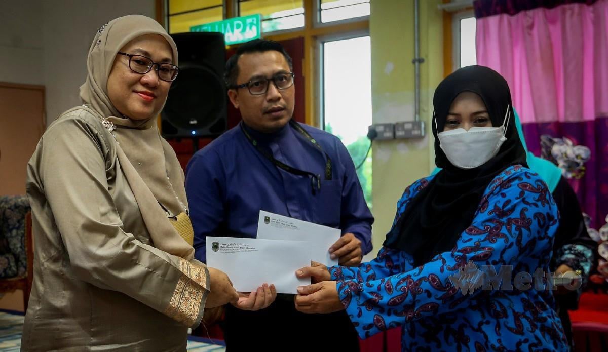 TIMBALAN Ketua Pengarah Pengurusan dan Pembangunan Kemas Malaysia, Rafea'ah Nahar (kiri) menyampaikan elaun latihan kepada Rahmah. FOTO Azrul Edham