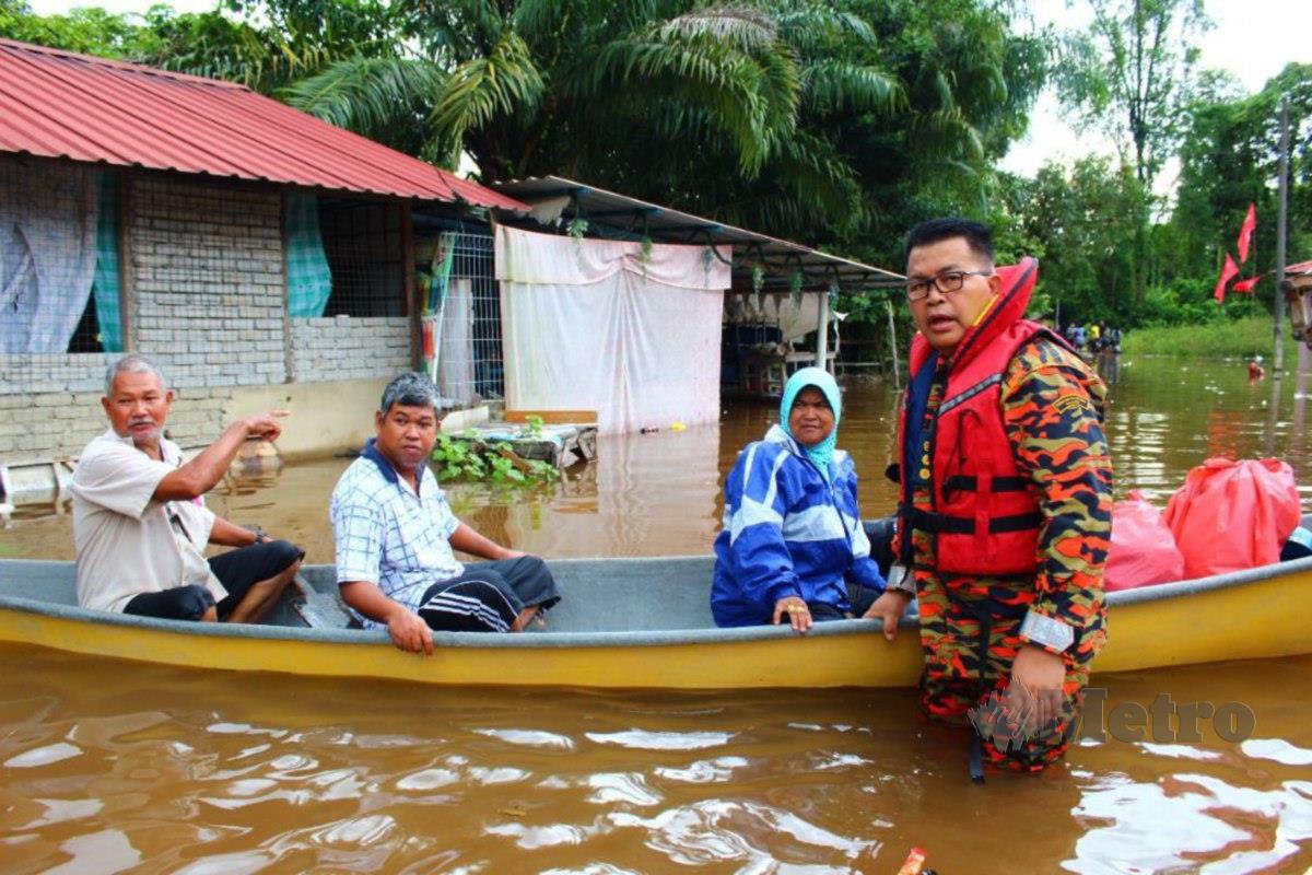 Jainal@Zainal membantu Mat Hussin dan keluarga yang terjejas akibat banjir di Kampung Kusar. FOTO Syaherah Mustafa 