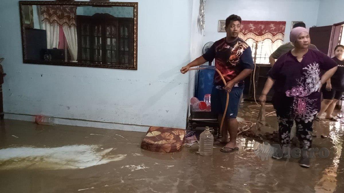 NOOR Arifin bersama ibunya membersihkan lumpur di ruang tamu selepas kejadian banjir kilat di Kampung Baru Sengkang. FOTO OMAR AHMAD