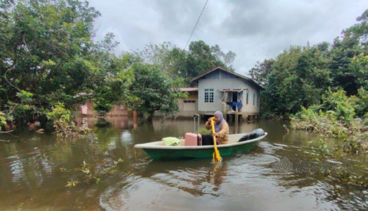 NUR Shairah mendayung perahu sendiri untuk mengangkut barang sebaik tiba dari Shah Alam susulan kediamanya dinaiki air di Kampung Tersang. FOTO SYAHERAH MUSTAFA.