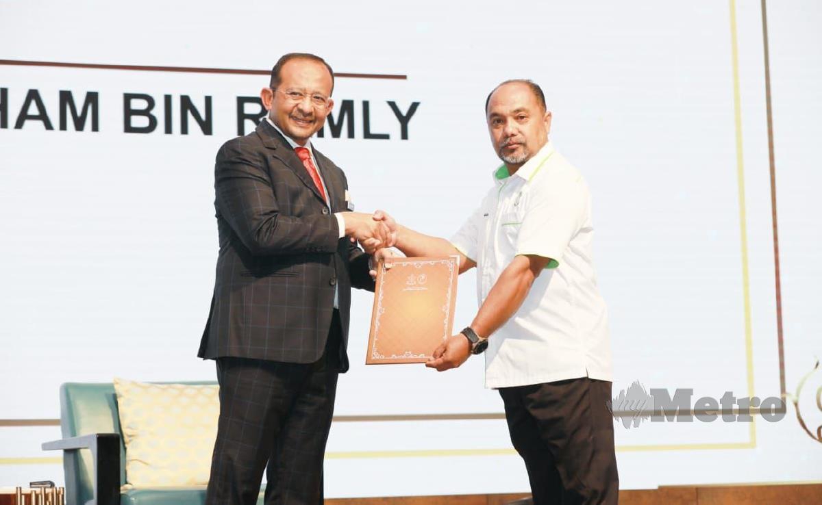 Hizamri Mohd Yasin menyampaikan Anugerah Perkhidmatan Cemerlang kepada  kakitangan JPNP, Badarul Hisham Ramly. FOTO MOHD RAFI MAMAT