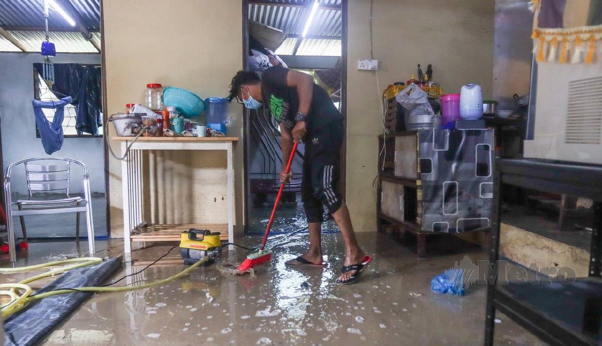 Penduduk membersihkan kawasan rumah mereka selepas dimasuki air. FOTO DANIAL SAAD
